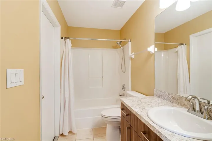 Full bathroom with vanity, tile patterned flooring, toilet, and shower / bathtub combination with curtain