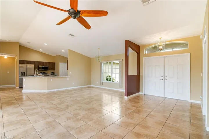 Entryway featuring light tile patterned flooring, ceiling fan with notable chandelier, sink, and lofted ceiling