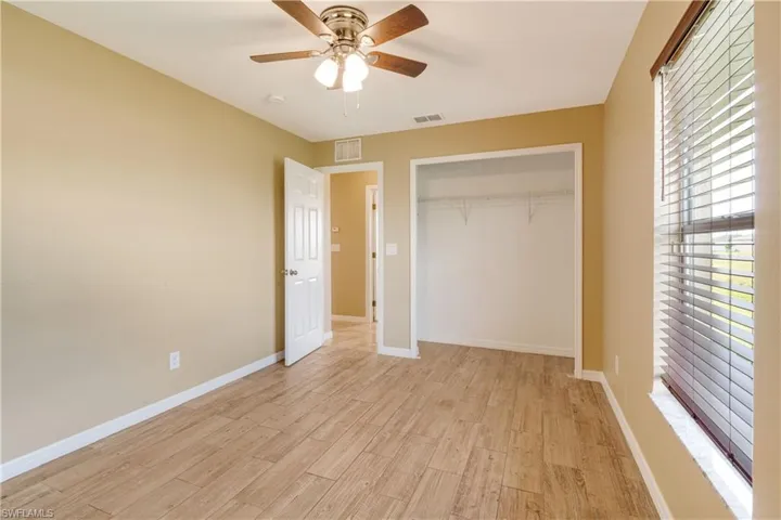 Unfurnished bedroom with ceiling fan, light wood-type flooring, and a closet