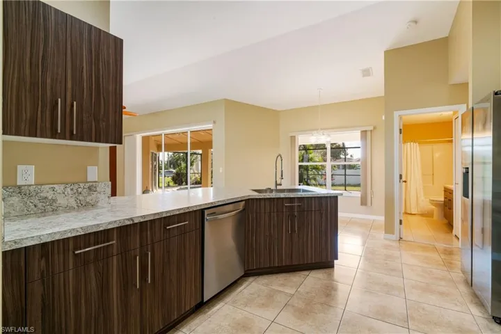 Kitchen featuring appliances with stainless steel finishes, kitchen peninsula, sink, and light tile patterned floors