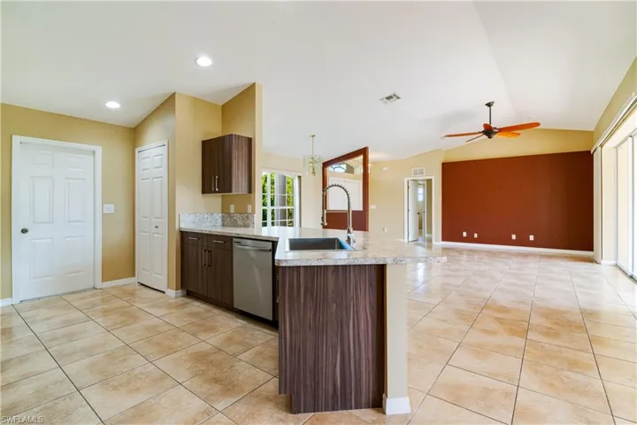 Kitchen with vaulted ceiling, ceiling fan, sink, and stainless steel dishwasher