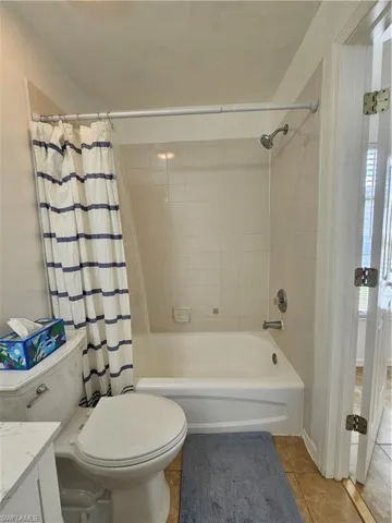 Full bathroom featuring a white bathtub with a tiled shower surround, a white toilet, and a vanity with a white countertop