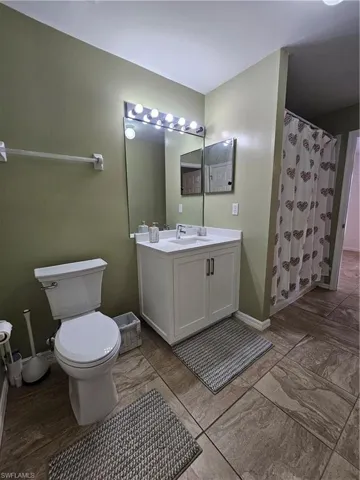 Bathroom featuring a white vanity with integrated sink, a large wall-mounted mirror, and tile flooring