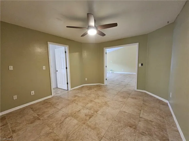Spacious room featuring neutral tile flooring, a ceiling fan with integrated lighting, and olive-toned walls