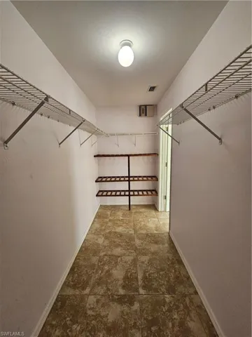 Spacious closet featuring tiled flooring, built-in wire shelving, and additional shelving units