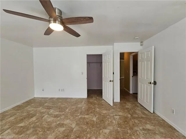 Spacious room featuring tile flooring, a contemporary ceiling fan with integrated lighting, multiple doorways, and crisp white walls