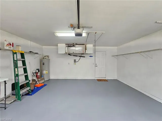 Garage featuring a painted concrete floor, built-in overhead storage, and wall-mounted shelving