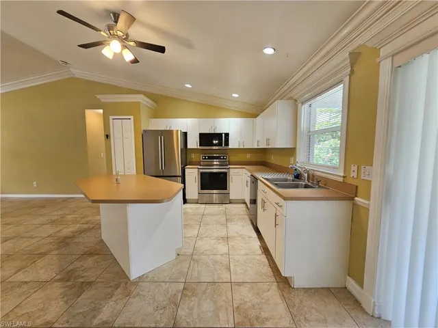 Kitchen featuring stainless steel appliances, white cabinetry, light-toned countertops, and tile flooring