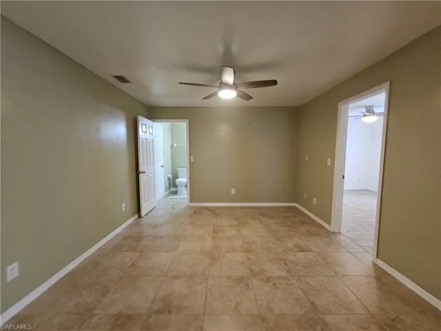 Spacious interior room featuring neutral wall paint, tile flooring, and a ceiling fan