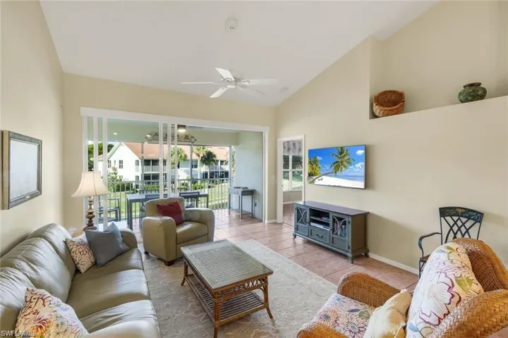 Living area featuring a ceiling fan, vaulted ceiling, and tile patterned flooring