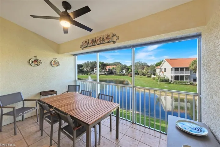 Sunroom with ceiling fan, a water view, and a balcony