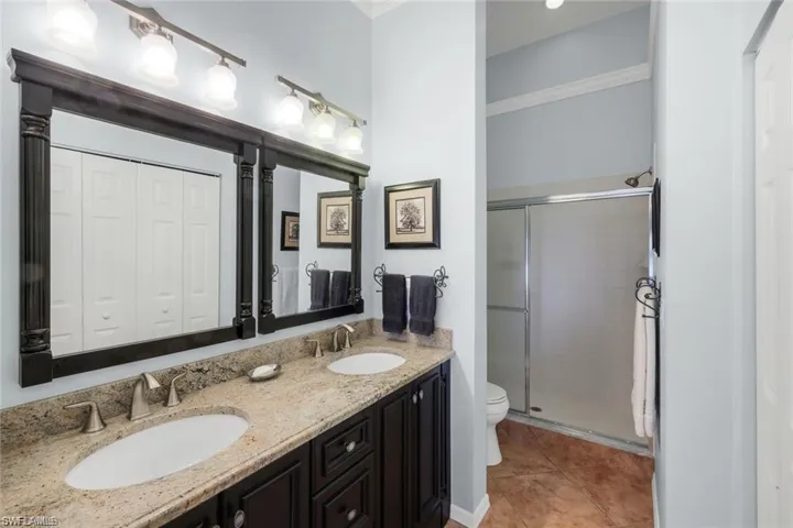 Full bathroom featuring double vanity, a closet, a stall shower, and light tile patterned floors