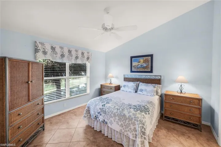 Bedroom with vaulted ceiling, a ceiling fan, and light tile patterned floors