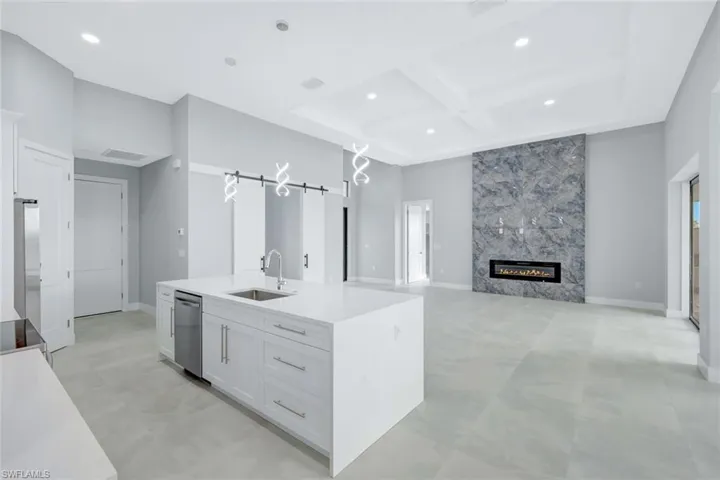 Kitchen with coffered ceiling, a barn door, light stone countertops, white cabinetry, and a fireplace