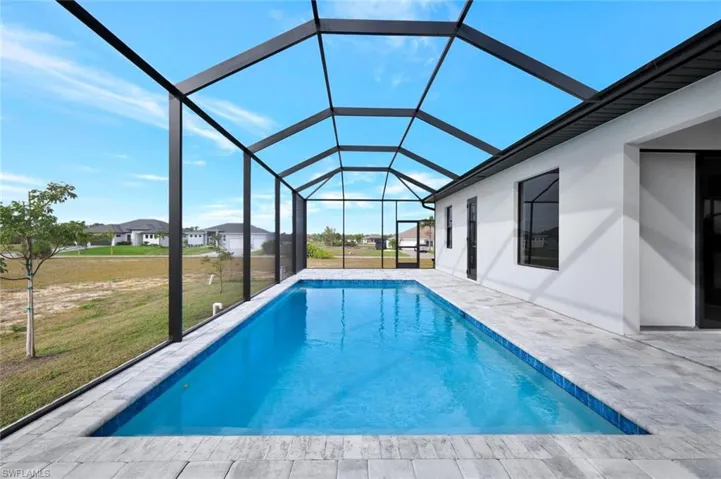 Swimming pool featuring a lawn, a sunroom, a lanai, and a patio area