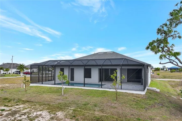 Back of property featuring glass enclosure, a yard, and a sunroom