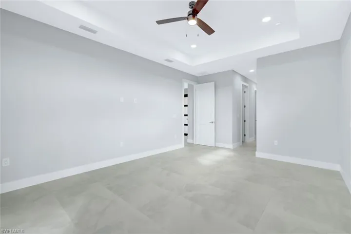 Unfurnished bedroom with a raised ceiling, recessed lighting, and ceiling fan