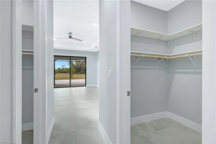 Walk in closet with ceiling fan and a tray ceiling