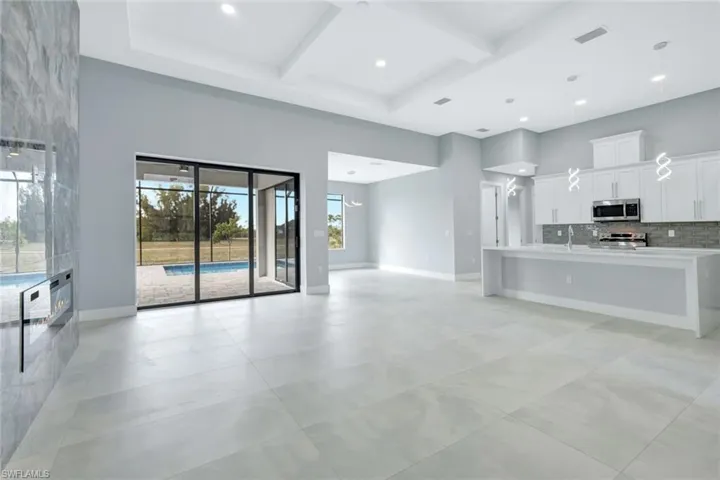 Unfurnished living room featuring coffered ceiling, a towering ceiling, beamed ceiling, and recessed lighting