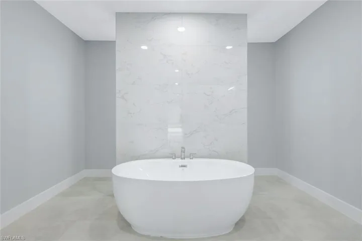 Full bath with baseboards and a soaking tub