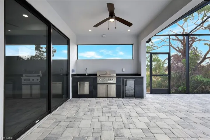 View of patio / terrace featuring a lanai, an outdoor kitchen, ceiling fan, and a sunroom