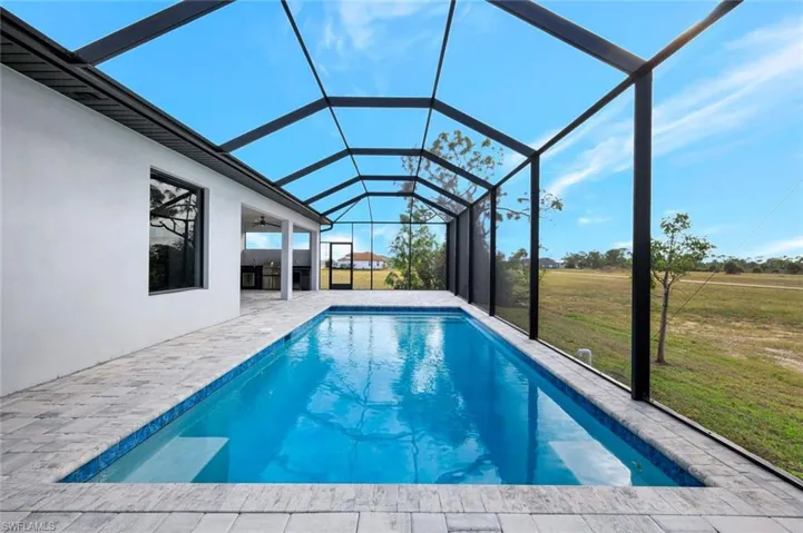 Outdoor pool with a yard, a sunroom, a patio, and a lanai