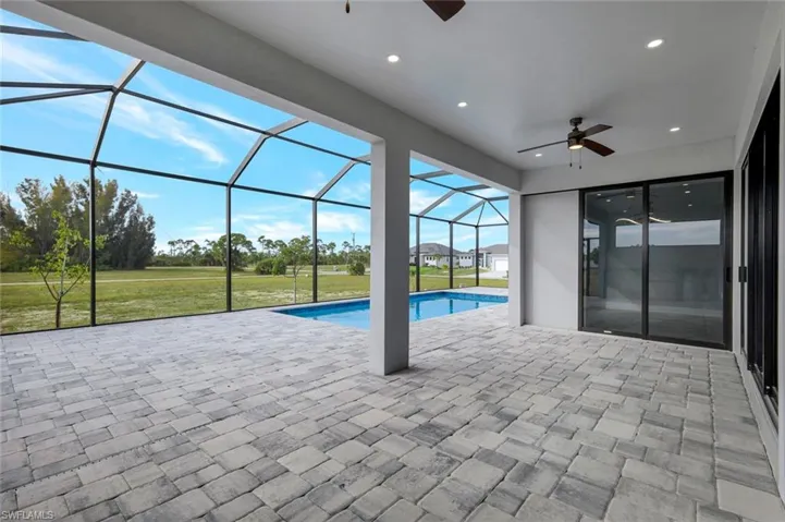 Swimming pool featuring a sunroom, a patio area, a lawn, and a lanai