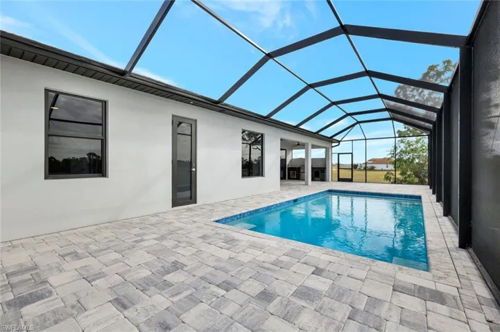 Swimming pool featuring a sunroom, a patio area, and glass enclosure