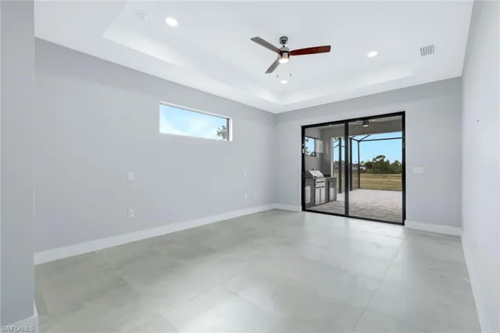 Unfurnished room featuring plenty of natural light, a ceiling fan, recessed lighting, and a raised ceiling