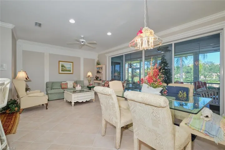 Tiled dining room featuring ceiling fan with notable chandelier and ornamental molding