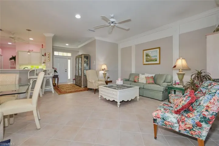 Living room featuring ceiling fan, ornamental molding, and light tile patterned floors