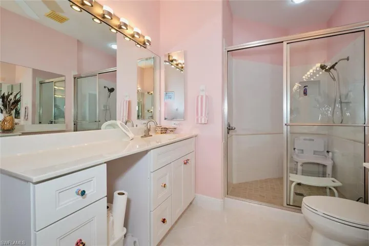 Bathroom featuring tile patterned flooring, toilet, an enclosed shower, and vanity