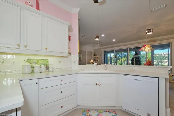 Kitchen with tasteful backsplash, crown molding, white cabinets, white dishwasher, and ceiling fan