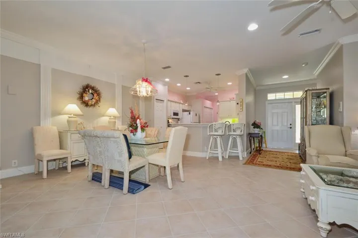 Tiled dining room with ceiling fan and ornamental molding