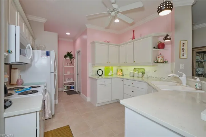 Kitchen with white appliances, white cabinetry, light tile patterned floors, and hanging light fixtures