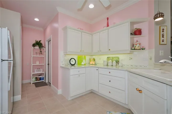 Kitchen featuring ceiling fan, backsplash, white cabinetry, white fridge, and light tile patterned flooring