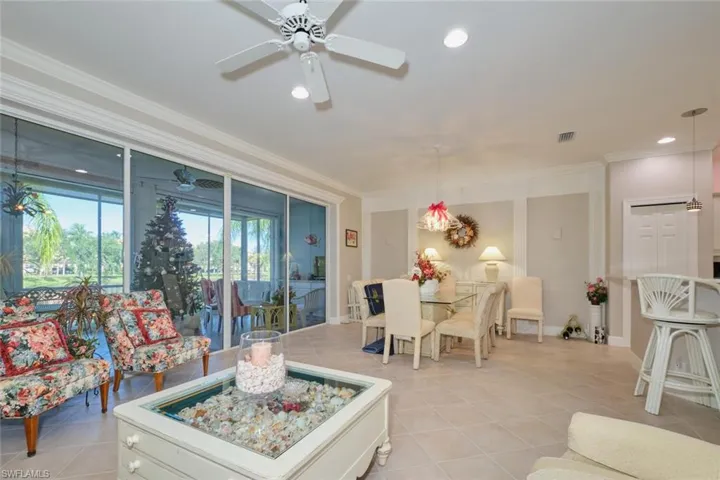 Tiled living room featuring ceiling fan and crown molding