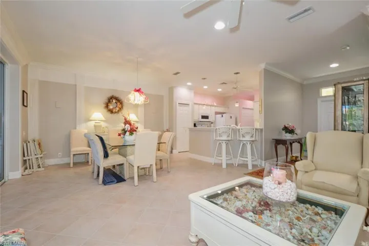 Tiled dining area featuring ceiling fan and ornamental molding