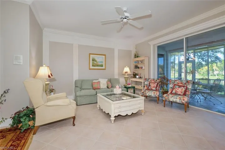 Tiled living room featuring ceiling fan and crown molding