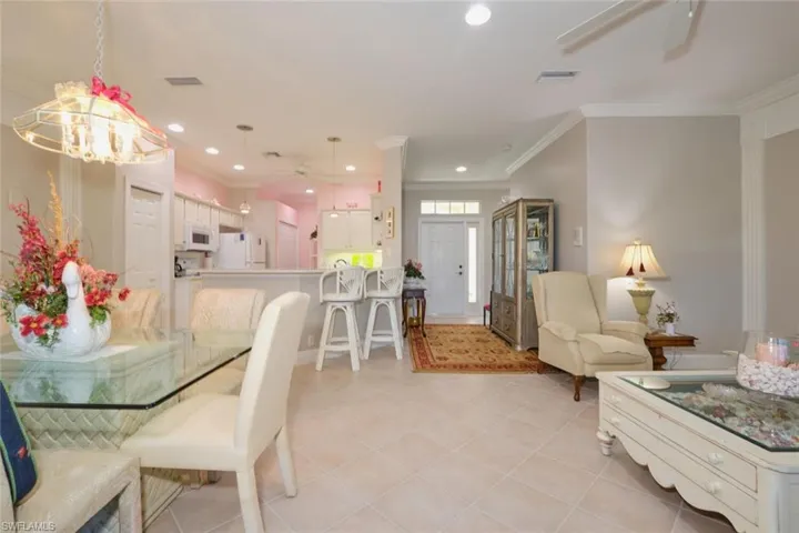 Tiled dining space featuring ceiling fan with notable chandelier and ornamental molding