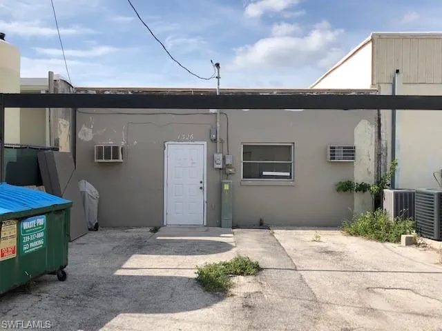 View of exterior entry with an AC wall unit, a patio, and central air condition unit