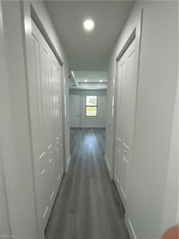 Corridor with dark wood-style floors and recessed lighting