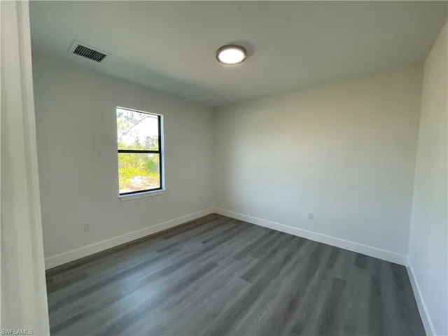 Spare room featuring dark wood finished floors and baseboards