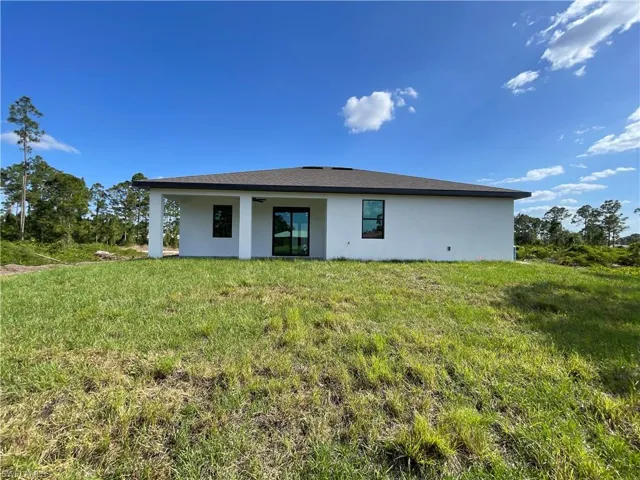 Rear view of house with a lawn and stucco siding