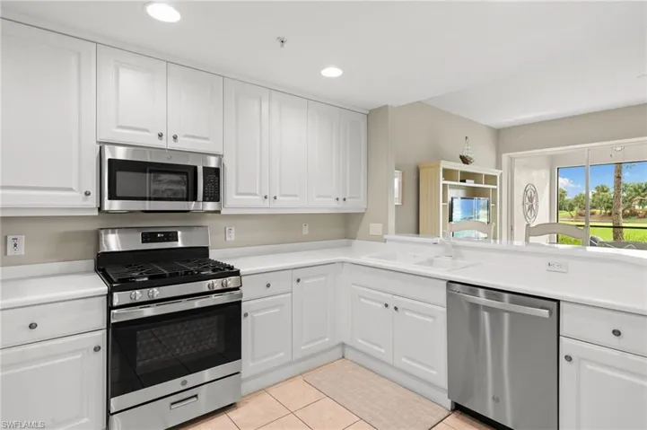 Kitchen with stainless steel appliances, white cabinets, light countertops, light tile patterned floors, and recessed lighting