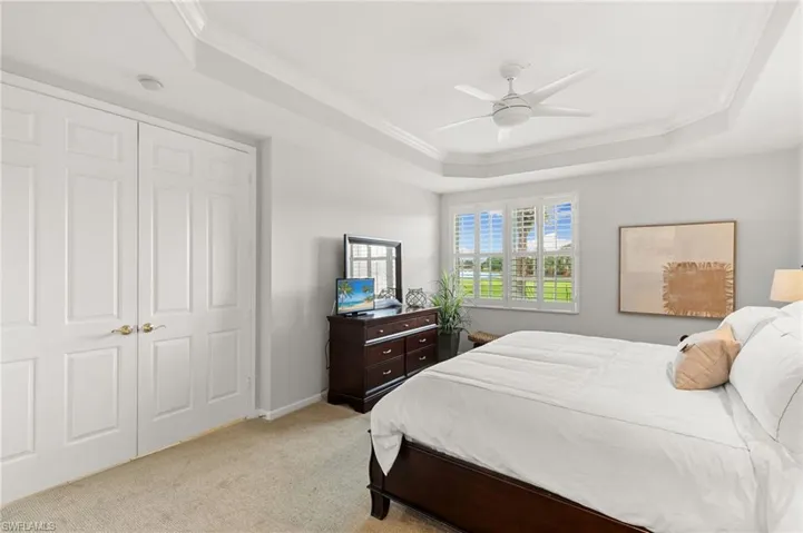 Bedroom featuring crown molding, carpet, a tray ceiling, ceiling fan, and a closet