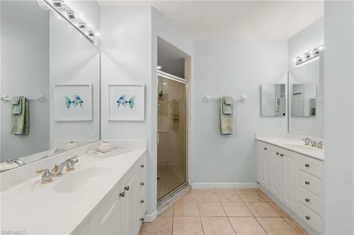 Full bath with a stall shower, light tile patterned floors, and two vanities
