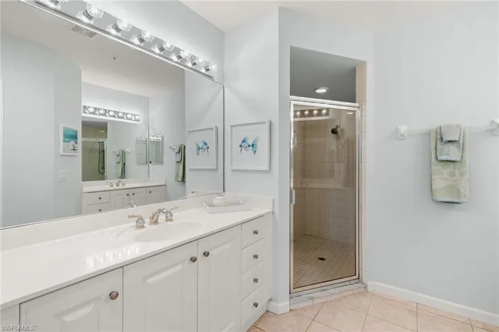Bathroom featuring light tile patterned floors, a stall shower, and vanity