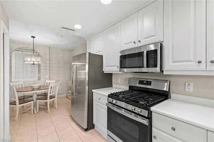 Kitchen with stainless steel appliances, white cabinetry, light countertops, light tile patterned flooring, and recessed lighting