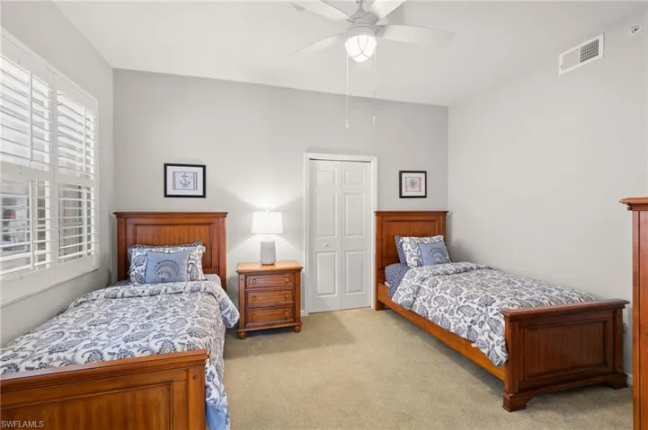 Bedroom with light carpet, a closet, and a ceiling fan